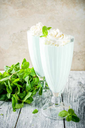 Summer refreshing cocktail, shamrock mint shake, sweet milk drink with fresh mint leaves, wooden background copy spaceの写真素材