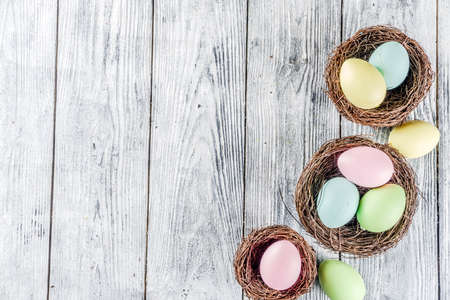 Pastel Easter background with tulip flowers and colorful painted Easter eggs. Top view, rustic white...