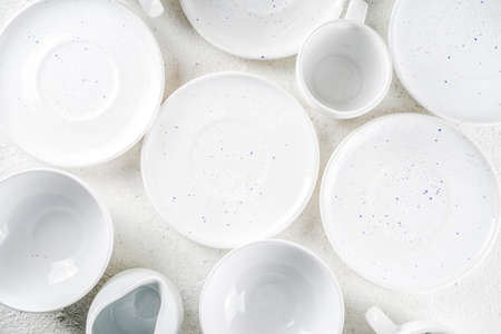 Assortment stack clean empty new white kitchen utensils, plates, bowls, cups mugs. On a white concrete backgroundの写真素材