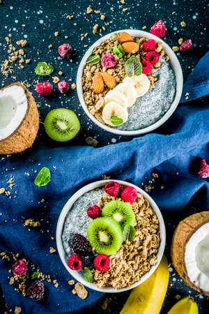 Homemade granola with chia seeds yogurt pudding, fresh fruit and berries, on dark blue concrete background copy spaceの写真素材