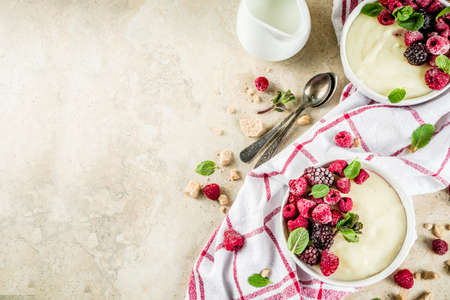 Two bowl with Semolina porridge with fresh berries, beige stone table copy space top viewの写真素材