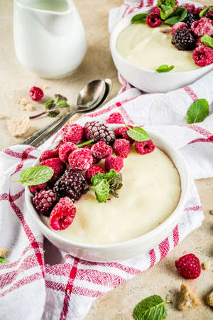 Two bowl with Semolina porridge with fresh berries, beige stone table copy space top viewの写真素材