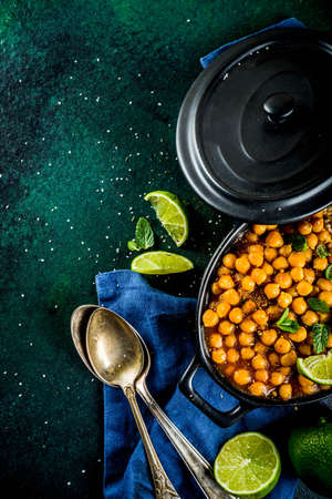 Vegan indian food, Sweet Potato and Chickpea curry, Chana Masala, with lime slices and spices on...