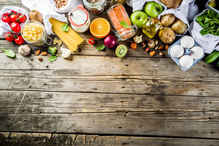 Zero waste shopping and sustanable lifestyle concept, various farm organic vegetables, grains, pasta, eggs and fruits in reusable packaging supermarket bags. copy space top view, wooden backgroundの写真素材