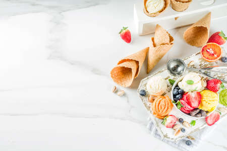 Colorful fruit and berry, nut, chocolate and vanilla ice cream, with waffle ice-cream cones, with...