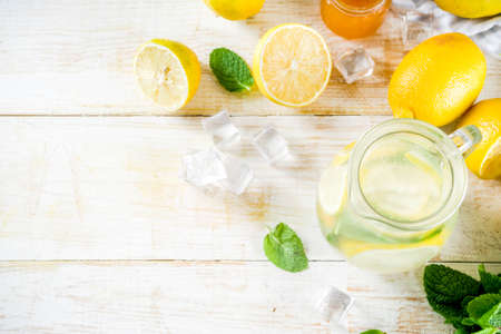 Homemade sour cocktail lemonade, with fresh lemons, mint and honey, white wooden background copy...