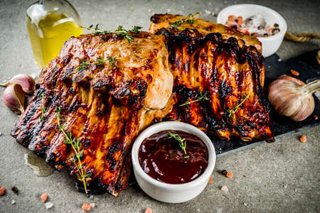 Grilled meat concept. bbq pork ribs with barbeque sauce, olive oil. fresh herbs on grey stone background copy spaceの写真素材