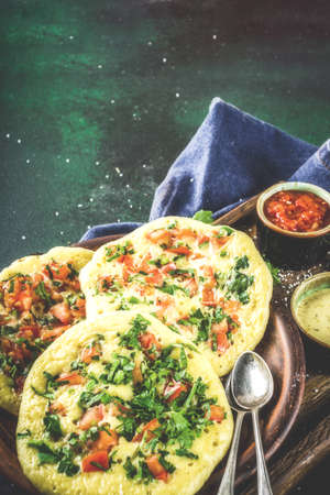 Indian traditional food recipes, Uttapam oats or semolina pancakes with fresh vegetables and herbs, dark blue background copy space top viewの写真素材