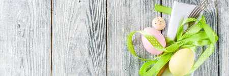 Easter table setting with eggs, ribbon and cutlery,wooden background copy space top view banner