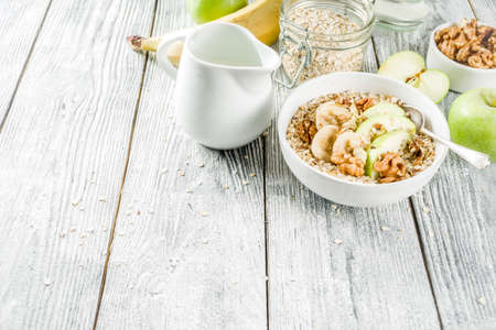 Healthy breakfast oatmeal with nuts ad fruits - apple, banana, walnuts, With milk on wooden background copy spaceの写真素材