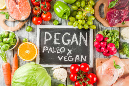 Trendy pegan diet - vegan plus paleo diet food concept, many fresh vegetables, fruits, raw beef and chicken meat, salmon fish, white wooden background top view copy spaceの写真素材