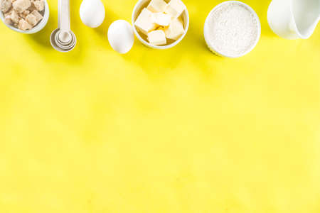 Baking ingredients and tools on trendy bright yellow background - flour, eggs, sugar, milk, butter, layout, flatlay top view copy spaceの写真素材