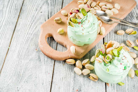 Vegan trend food. Homemade pistachio yogurt ice cream with fresh pistachios. On a white wooden table,の写真素材