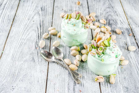 Vegan trend food. Homemade pistachio yogurt ice cream with fresh pistachios. On a white wooden table,の写真素材