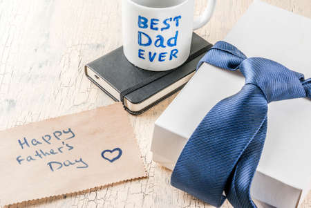 Father's Day gift concept, greeting card background, gift box, tie decoration, mug with inscription Best Dad Ever, notebook, copy spaceの写真素材
