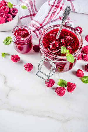 Homemade raspberry jam in two jars with raspberries and mint