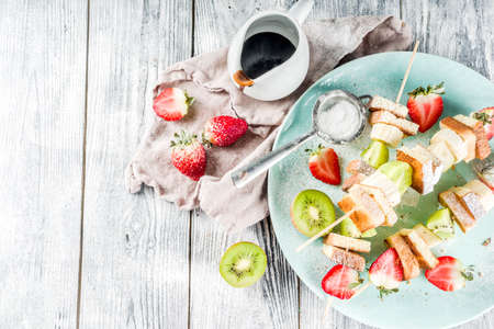 Summer breakfast snack. Fruit vegan dessert kebabs on skewers with toast French fried bread, fruits and berries. With powdered sugar and chocolate sauce.の写真素材