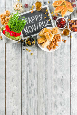 Happy Nowruz holiday background. Celebrating Nowruz sweets and treats- baklava, various dried fruits,  nuts, seeds, wooden background with green grass, copy space top viewの写真素材