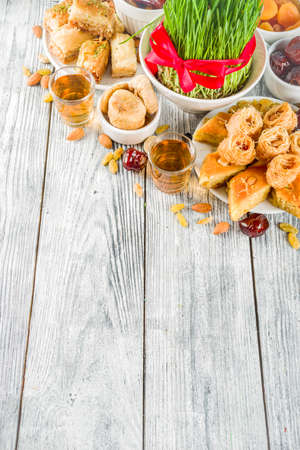 Happy Nowruz holiday background. Celebrating Nowruz sweets and treats- baklava, various dried fruits,  nuts, seeds, wooden background with green grass, copy spaceの写真素材