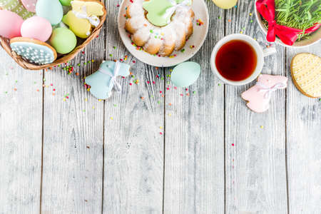Easter table setting concept, festive table with decoration of young grass, cake, pastel colored eggs, homemade cookies in shape of eggs, bunny rabbits. On a wooden background, copy spaceの写真素材