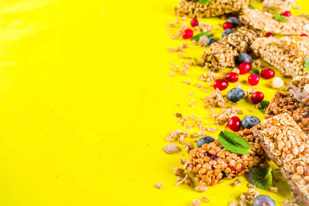 Cereal granola bars with nuts, fruits and berries, bright yellow background top view copy spaceの写真素材