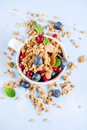 Small cup with breakfast oat granola, cereal muesli, nuts and berries. Healthy breakfast or snack...