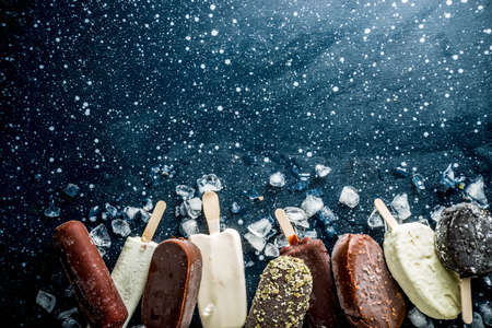 Assortment of various  ice cream, vanilla and chocolate, with nuts, on a dark concrete background...