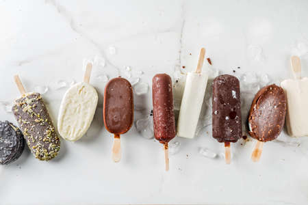 Assortment of various   ice cream, vanilla and chocolate, with nuts, on a dark concrete background...