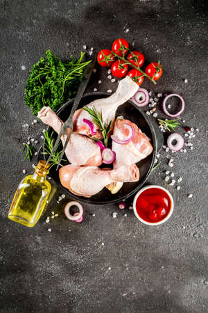 Raw chicken legs ready for cooking, with fresh vegetables, herbs and spices, black concrete background top view copy spaceの写真素材