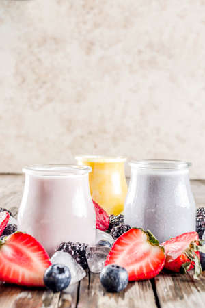 Summer fruits and berries smoothie drink. Vitamin diet snack beverage, with blueberries, strawberries, blackberries, kiwi. Dark blue concrete background copy spaceの写真素材