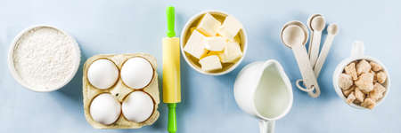 Baking ingredients and tools on trendy bright blue background - flour, eggs, sugar, milk, butter, layout, flatlay top view copy space bannerの写真素材
