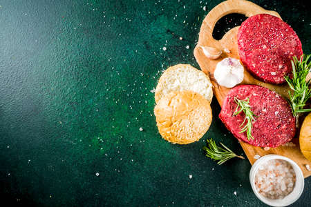 Raw beef burger cutlets, with spices and herbs, dark concrete background copy spaceの写真素材