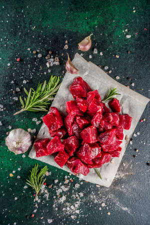 Raw beef meat with spices and herbs, dark concrete background copy space