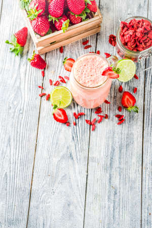 Healthy blended drink. Organic diet smoothie with lime, strawberry and goji berries, wooden background copy spaceの写真素材