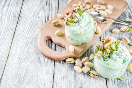 Vegan trend food. Homemade pistachio yogurt ice cream with fresh pistachios. On a white wooden table,の写真素材