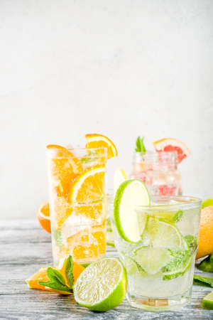 Summer refreshment drinks. Four types of citrus lemonade or mojito cocktail - orange, lime, lemon, pink grapefruit. Infused citrus water. On a wooden white background,の写真素材