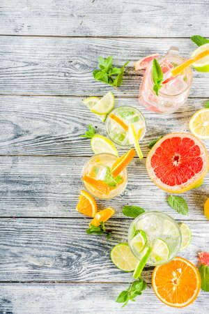 Summer refreshment drinks. Four types of citrus lemonade or mojito cocktail - orange, lime, lemon, pink grapefruit. Infused citrus water. On a wooden white background,の写真素材