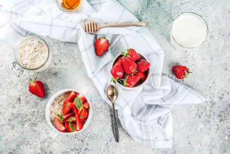 Healthy summer breakfast, overnight oatmeal with fresh strawberry and milk, grey stone background aboveの写真素材
