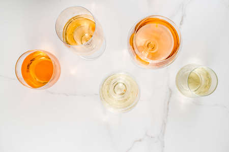 Trendy orange wine, with white wine in different glasses, white concrete background copy spaceの写真素材