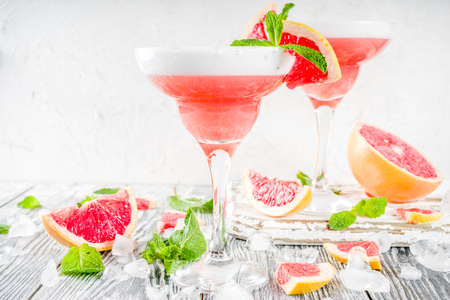 Summer trend alcohol drink. Cold citrus martini cocktail. Aperol spritz, with fresh grapefruit and mint. Wooden white background, copy spaceの写真素材