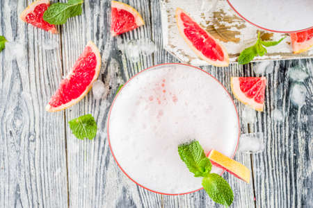 Summer trend alcohol drink. Cold citrus martini cocktail. Aperol spritz, with fresh grapefruit and mint. Wooden white background, copy spaceの写真素材