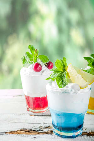 Summer cold drinks. Colorful Italian cream soda cocktails over white wooden background copy spaceの写真素材