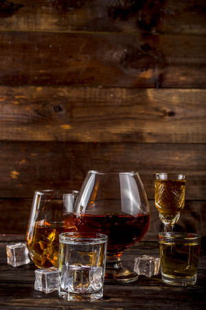 Assortment various hard and strong alcoholic drinks in different glasses: vodka, cognac, tequila, brandy and whiskey, grappa, liqueur, vermouth, tincture, rum, etc. Wooden background copy spaceの写真素材