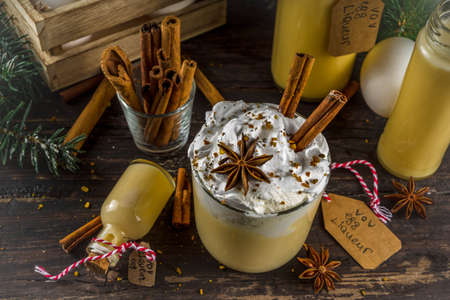 Christmas Bombardino Livigno cocktail with egg liqueur VOV and rum. With cinnamon, spices. Wooden background with christmas decorations, copy spaceの写真素材