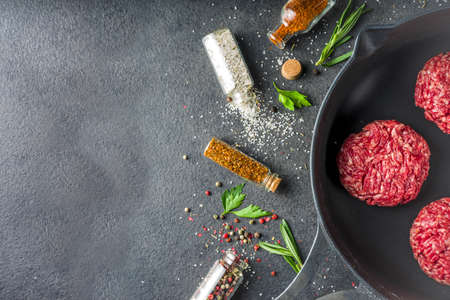 Raw minced meat beef burger cutlets. Cooking meat and burgers background with olive oil. herb, spices, black stone or concrete table, above, copy spaceの写真素材