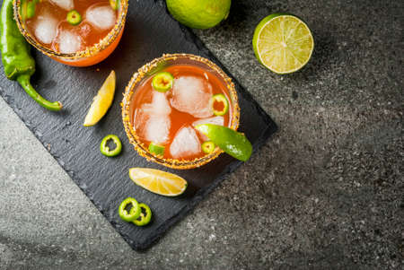Alcohol. Traditional Mexican South American cocktail. Spicy michelada with hot jalapeno peppers and lime. On a dark stone table. Copy space top viewの写真素材