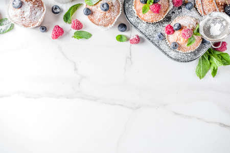Homemade vanilla muffins or cupcakes with fresh berries on  white marble backgroundの写真素材