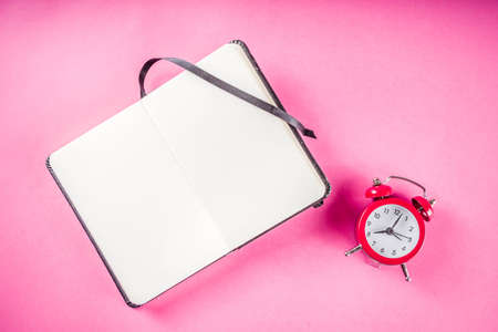 Alarm clock with notepad on bright pink table. Performance, work or study concept, Creative flatlay...