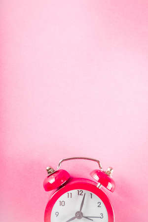 Small red alarm clock on bright pink table. Performance, work or study concept, Creative flatlay...