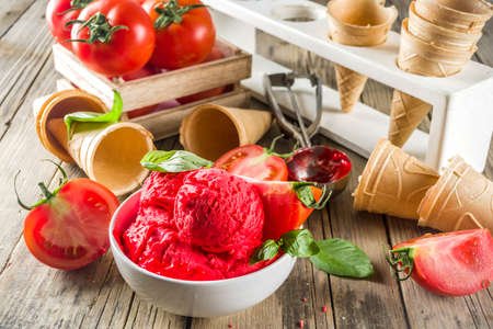 Vegetable gelato. Tomato ice cream with fresh tomatoes and basil and leaves, old rustic wooden background. の写真素材